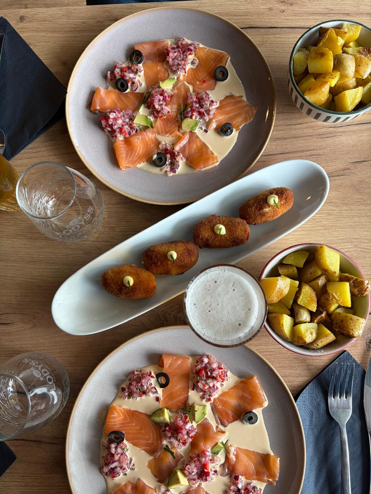 Salmon carpaccio with avocado, black olives and red onion salsa, alongside croquetas and patatas